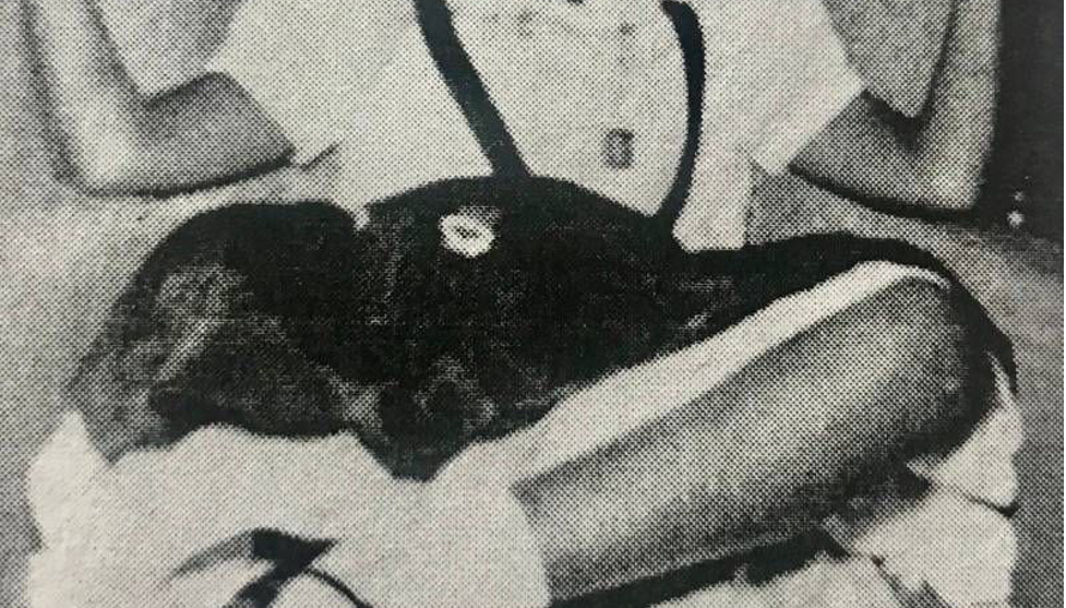 Girl sitting crosslegged in white shirt and black skirt