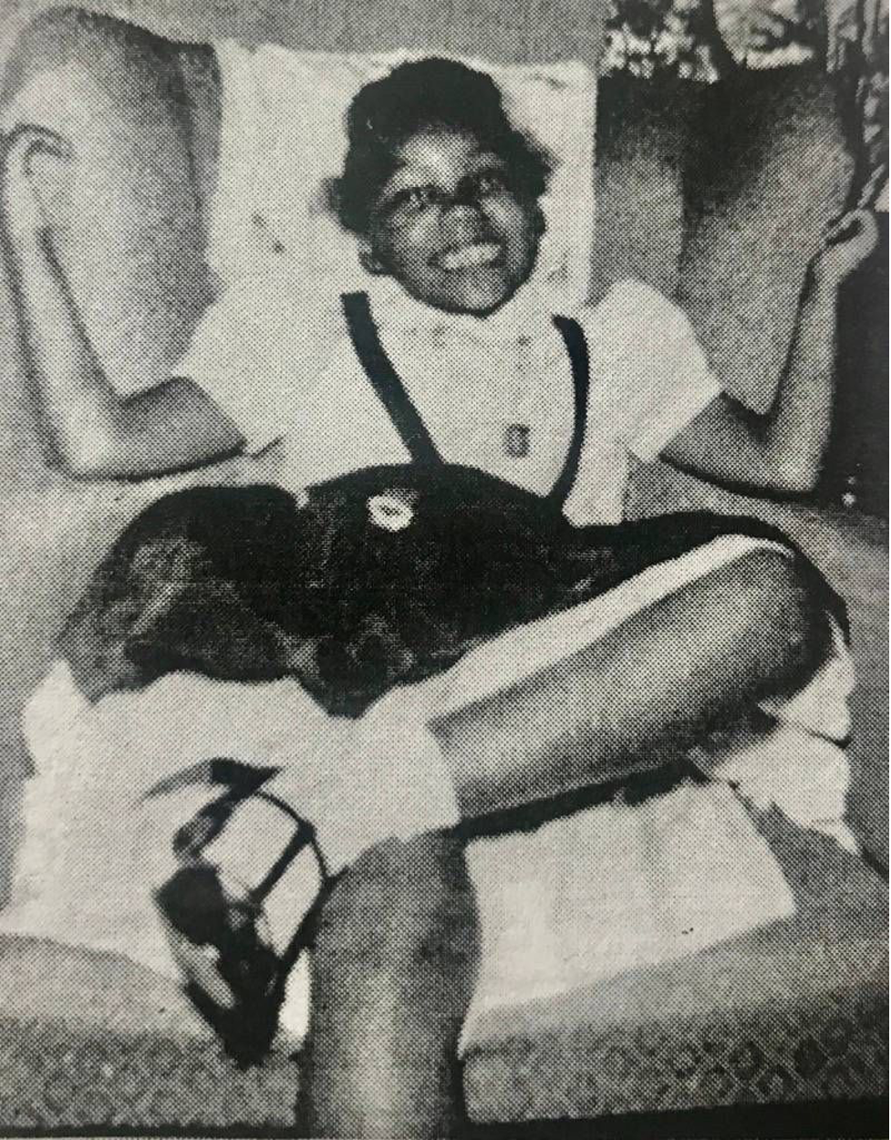 Girl sitting crosslegged in white shirt and black skirt