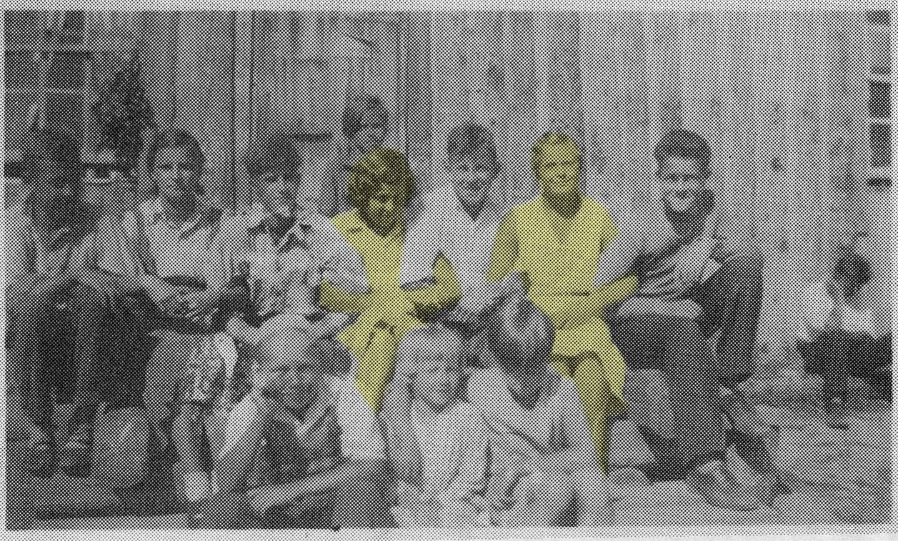 A group of children sitting and locking arms. Two children are highlighted in yellow.