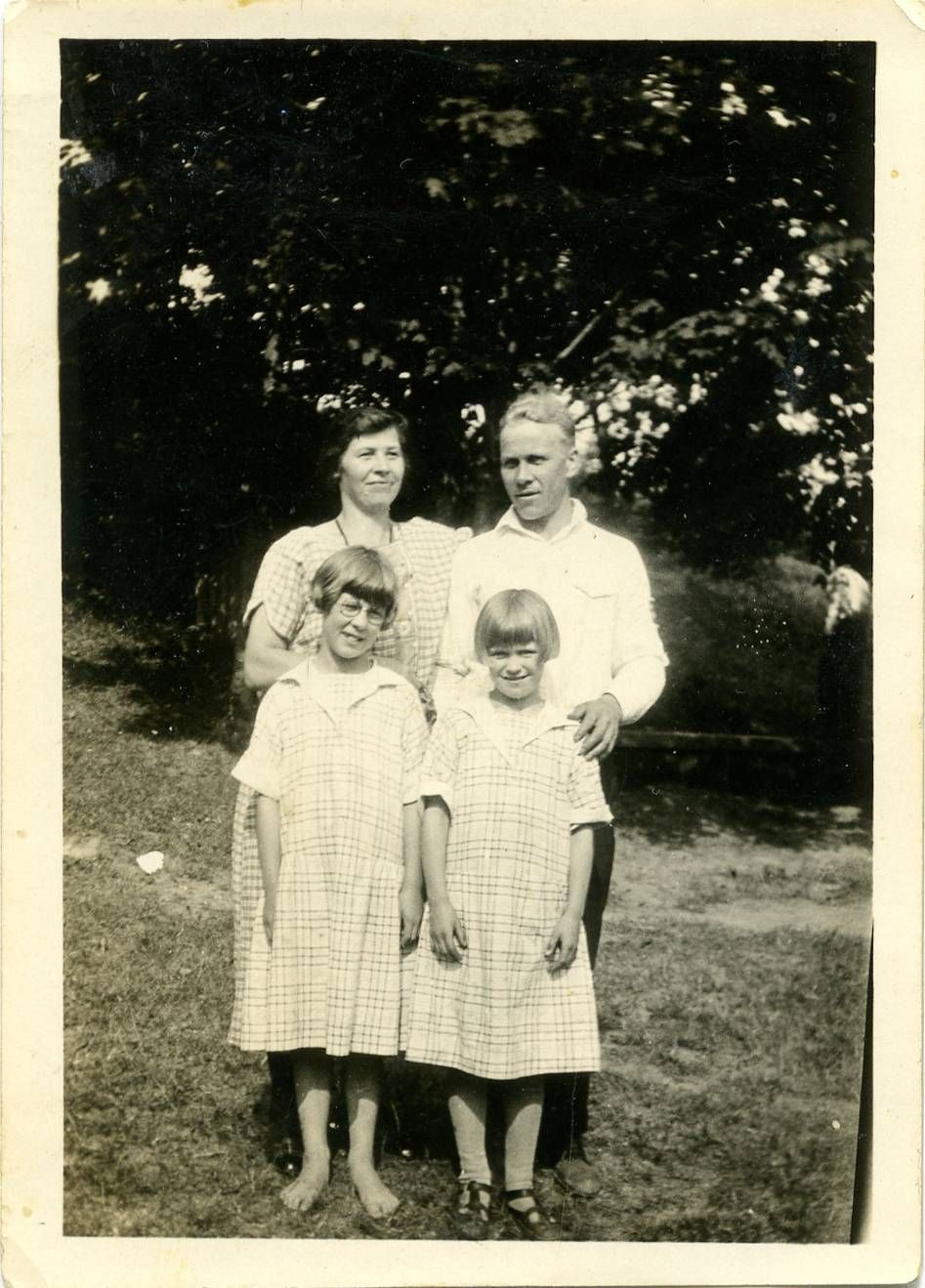 A man, woman, and two girls dressed formally and standing in a field of grass