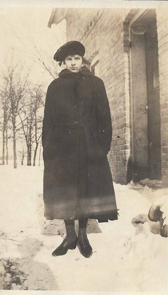 Young woman dressed in a long coat and wearing a hat