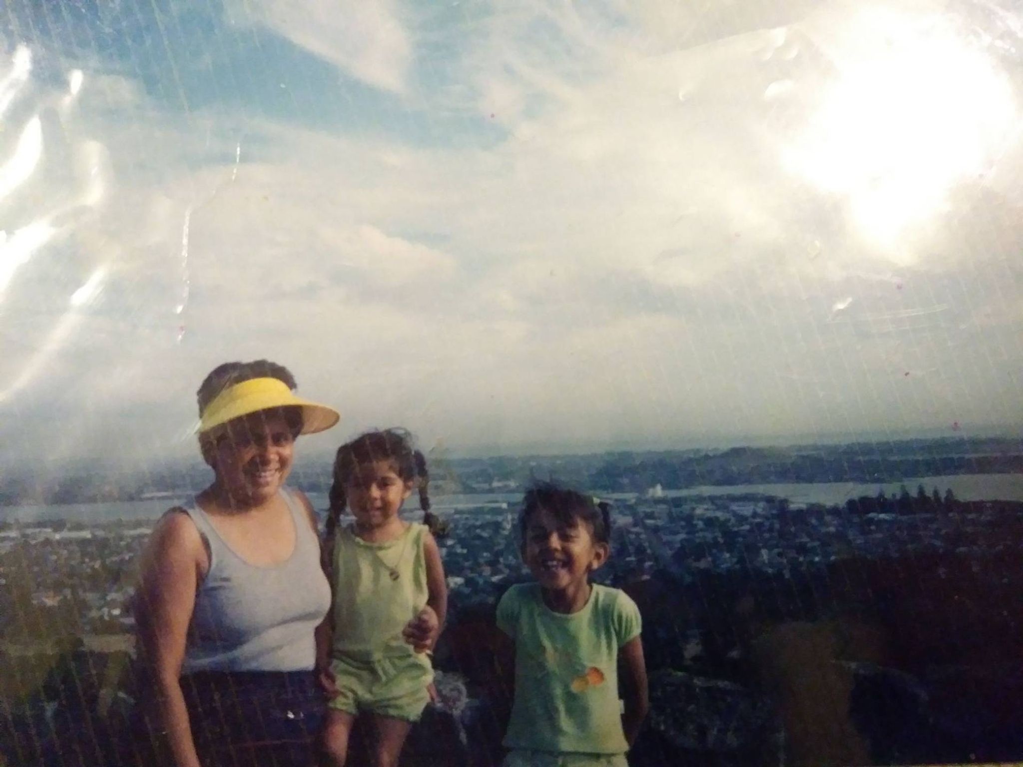 A family of three smiling outside with the sun shining