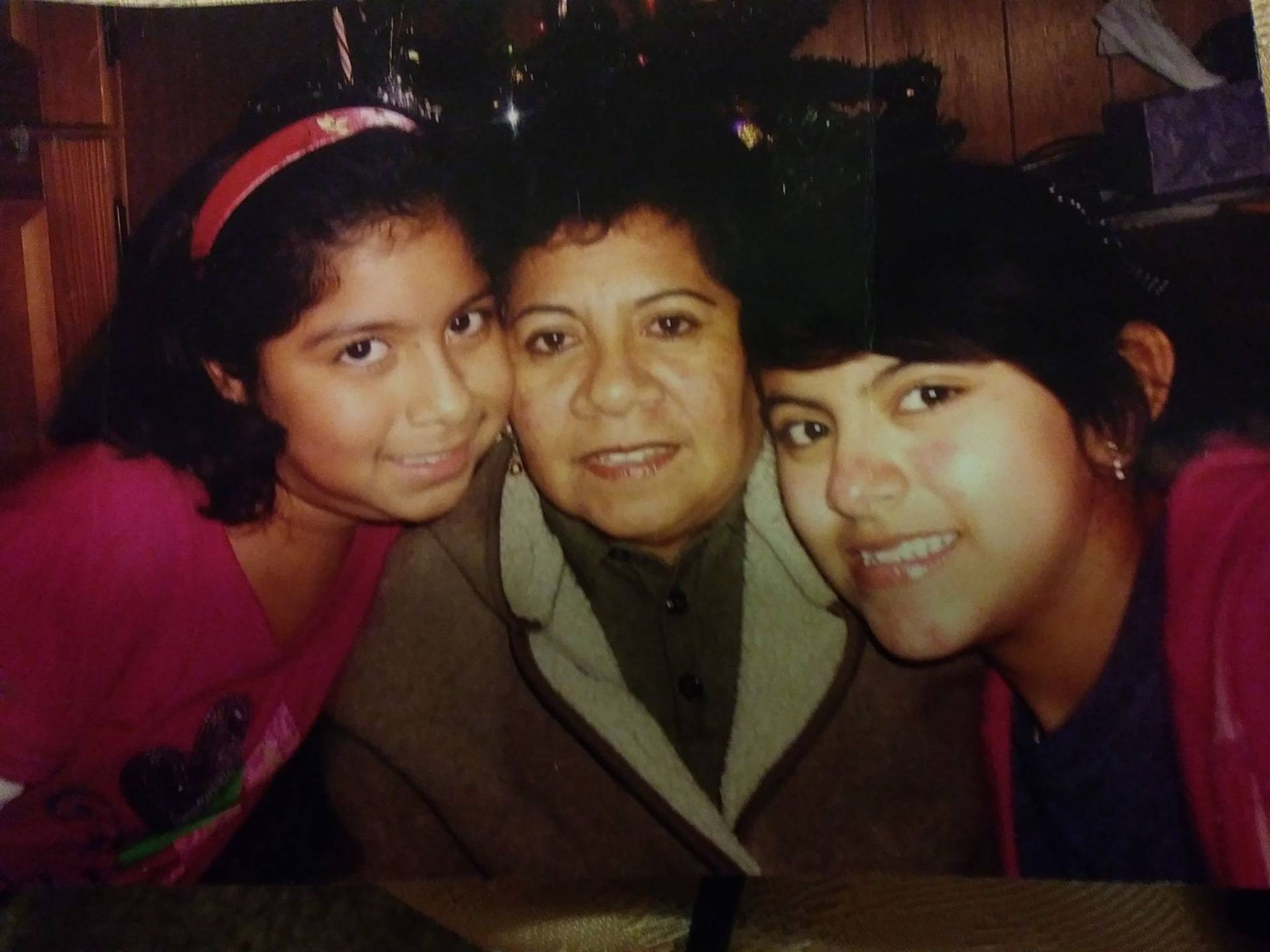 Two younger girls smiling with an older woman wearing a jacket