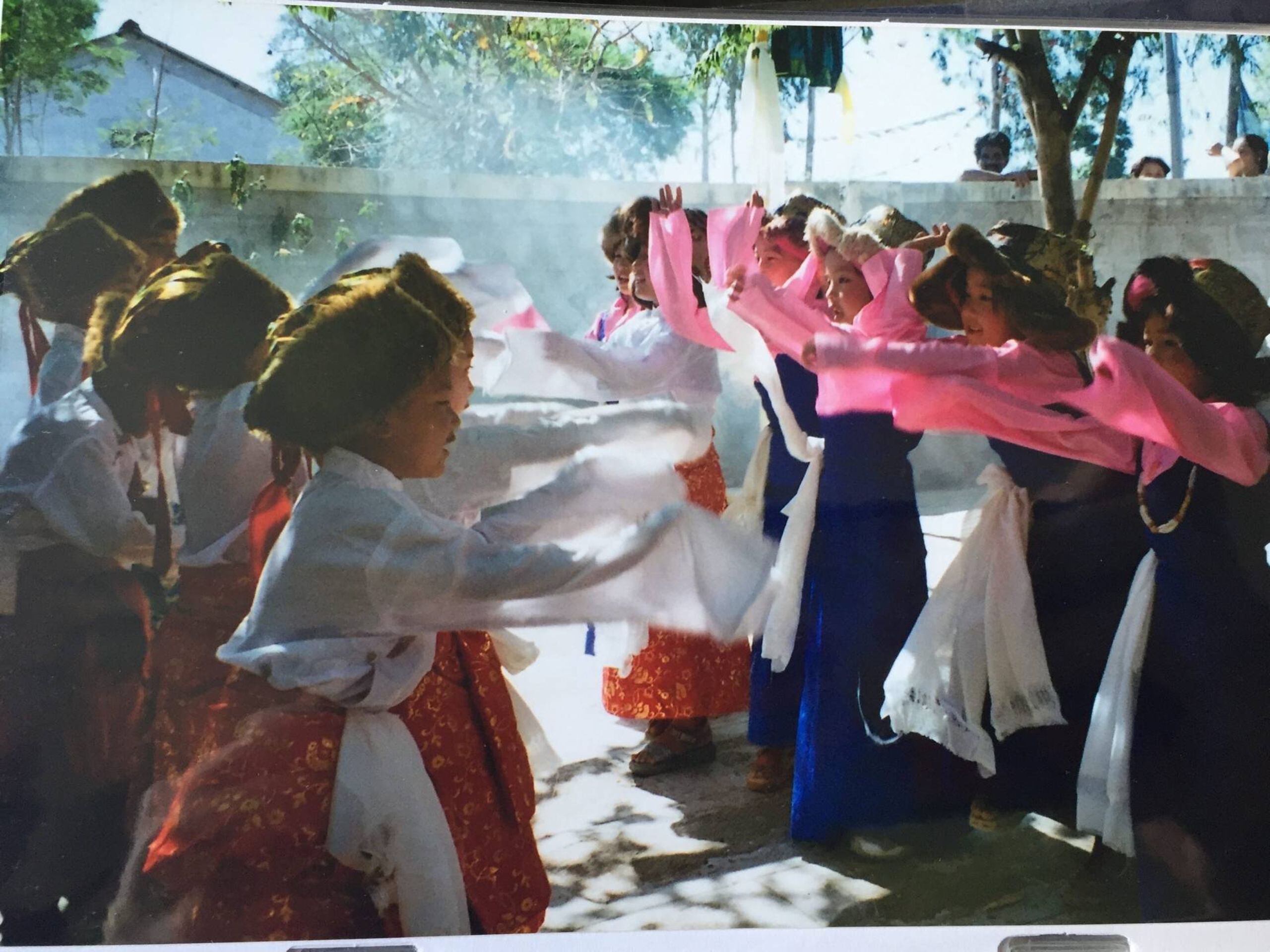 Row of children dressed in traditional Tibetan clothing dancing