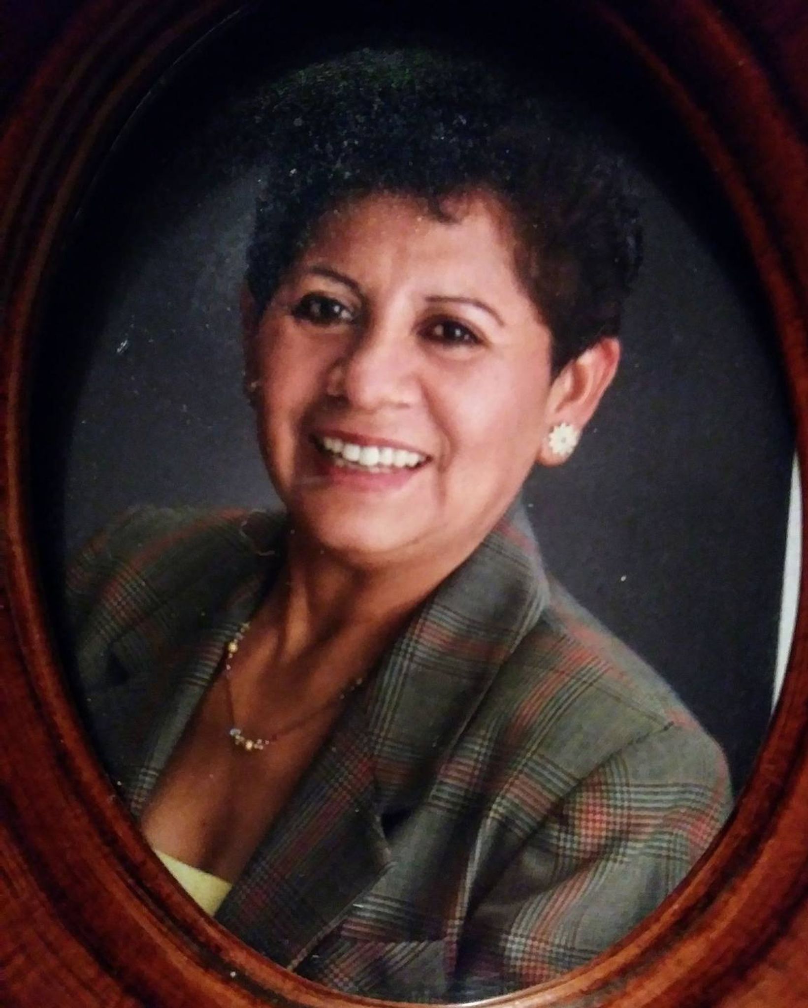 Older woman in a green suit and a diamond earing who is smiling