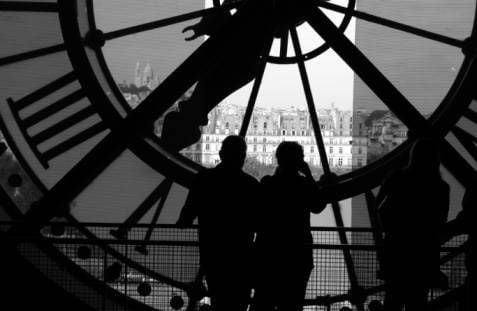 people silhouetted against big clock face