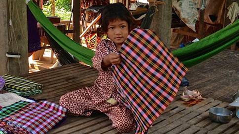 A young girl shows off the fabrics created by her family
