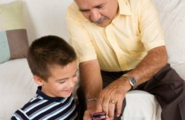 grandfather teaching grandson how to use cell phone