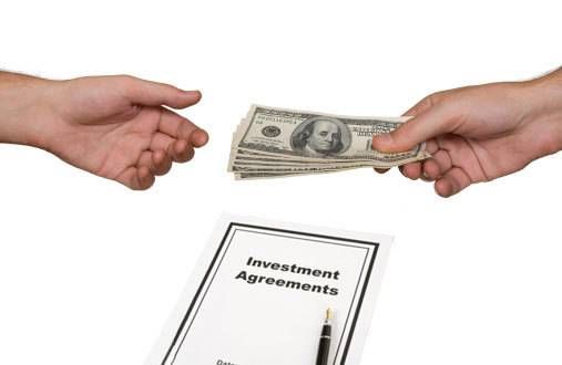 money handed from one hand to another over investment contract papers