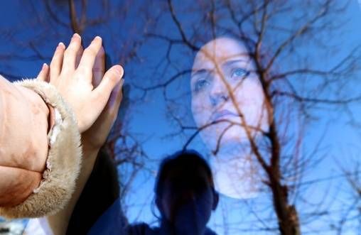 woman with outstretched hand touching her own reflection