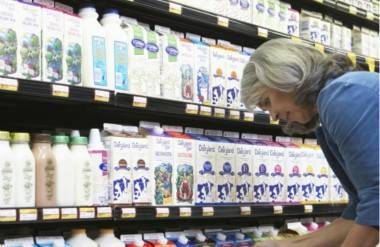 woman reading milk carton in dairy aisle of market
