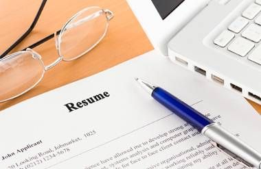 Resume next to pen, glasses and computer