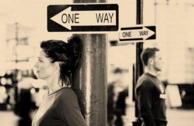 woman under a one way signpost, a man under an opposite one way signpost