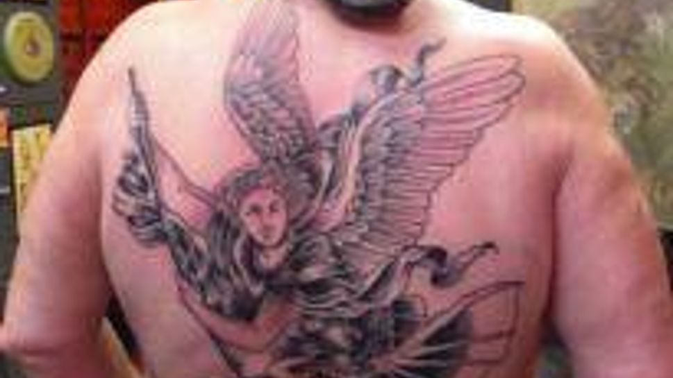 large back tattoo of angel holding down devil
