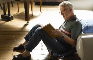 Mature man sits on the floor, reading