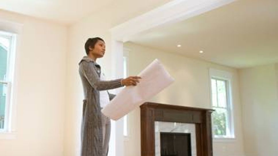 Woman standing in house looking at blueprints