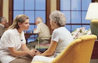 a nurse speaking to a woman in a nursing home
