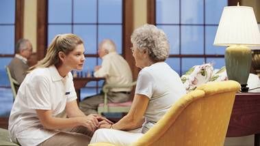 a nurse speaking to a woman in a nursing home