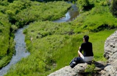 hiker sitting on hilltop overlooking river below