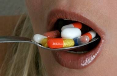 close up woman taking spoonful of pills