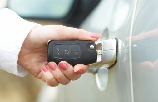 womans hand holding key in car door lock