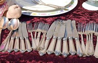 Items on a table at an estate sale, including silverware