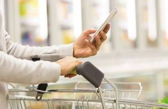 Woman browses on her smartphone while shopping in a grocery store