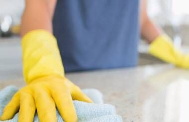 a person wearing gloves and cleaning a countertop