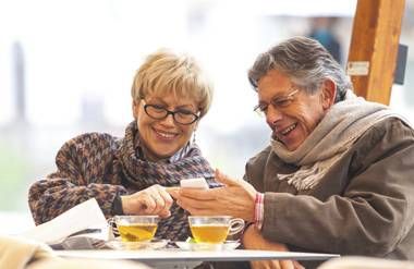 Couple looking at smartphone and enjoying tea