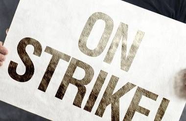 Man holding 'on strike!' sign