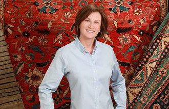 Connie Duckworth stands in front of Afghan rugs she now sells after leaving a ca