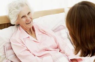 An aging mother in bed talking to her adult daughter about end-of-life issues.