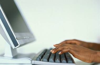 a black woman's hands typing on a computer