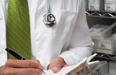 Doctor writing notes on medical chart