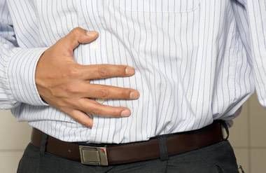 Man with his hand on his stomach, experiencing discomfort