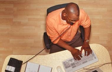 Man talking on phone and working on computer in office