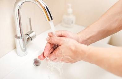 person washing hands under water