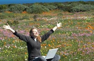 Woman sitting in field with computer