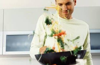 a young man tossing vegetables in a wok