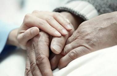 A younger woman holding an aging person's hands