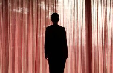 Silhouette of woman standing in front of red curtains