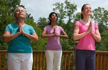 Three women doing yoga on terrace