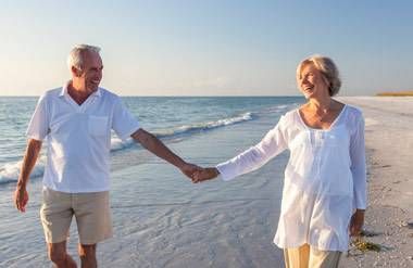 Smiling mature couple walking on the beach, hand-in-hand