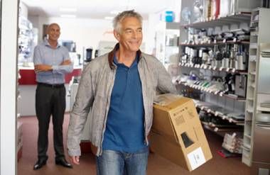 a man holding a box walking out a store smiling