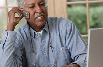 A South Asian older man listening to a robo call about a product recall.