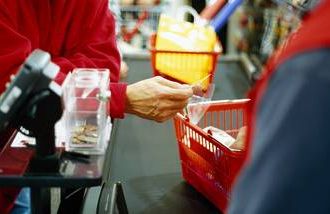 An older man giving a discount card to a cashier in the grocery store. 
