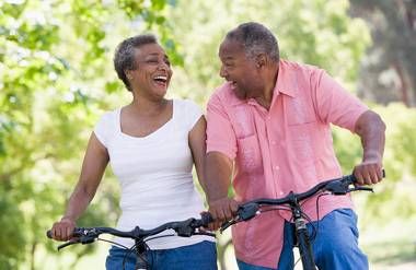 A mature African-American couple having fun on a bike ride.