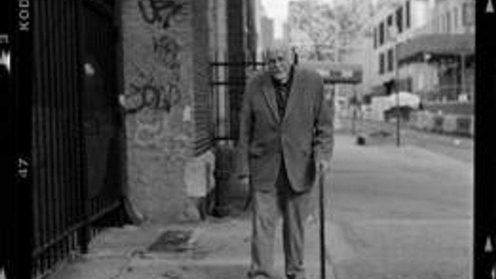 joe white standing on a sidewalk with a cane