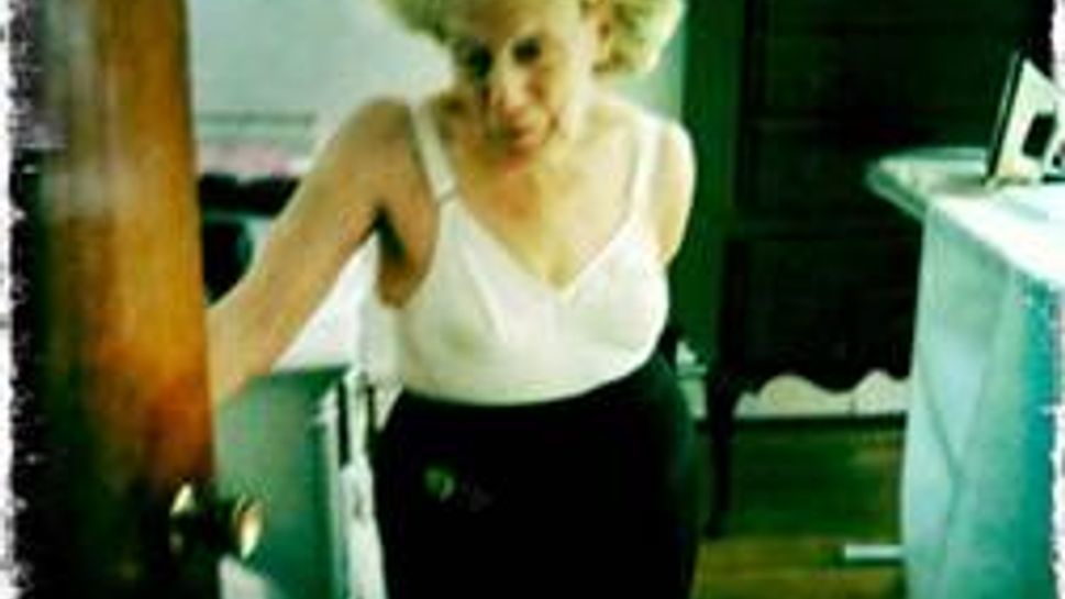 mary white in a camisole, hair net, and black skirt ironing