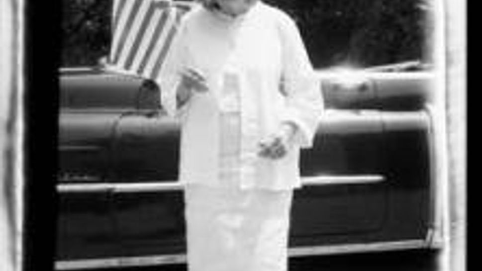 mary white in a white pants outfit holding the American flag